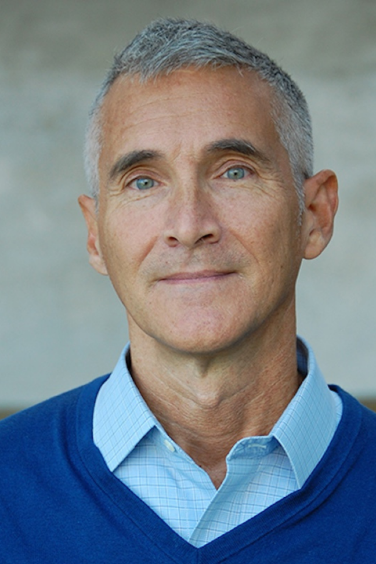 A headshot photo of a man with grey hair wearing a collared shirt