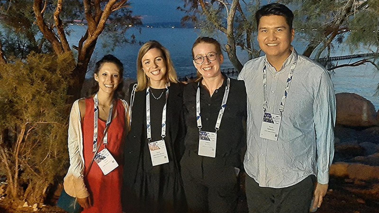 Four Columbia attendees standing outside in the evening in front of a body of water