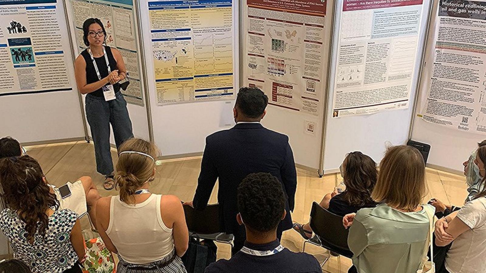 woman presenting a poster to a group of individuals