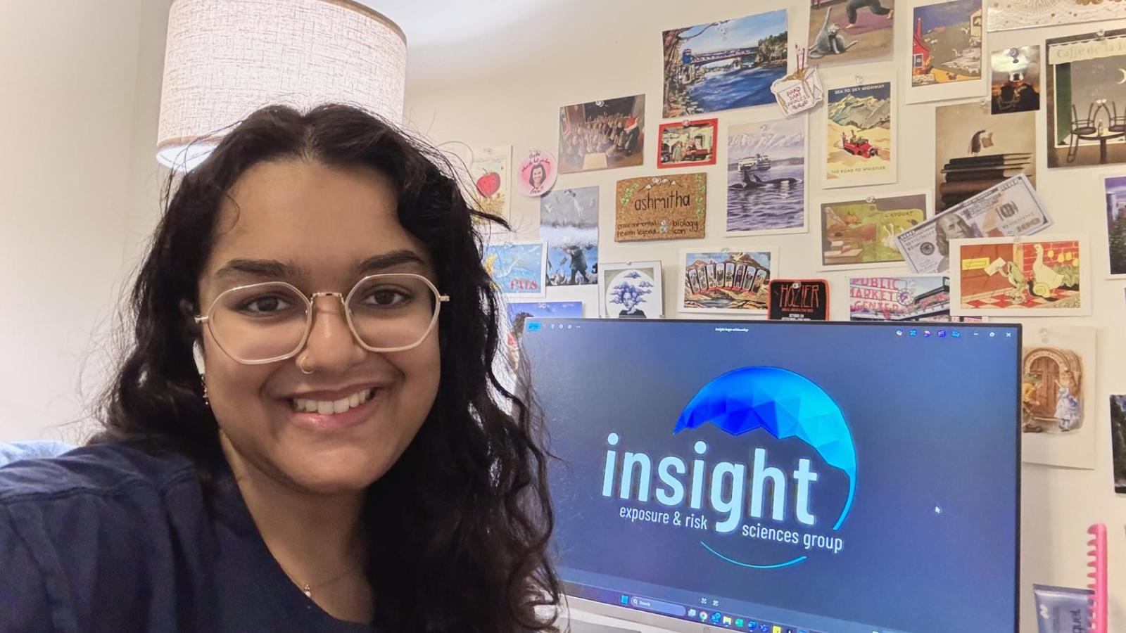 student sits in a room with a computer behind her showing an Insight logo