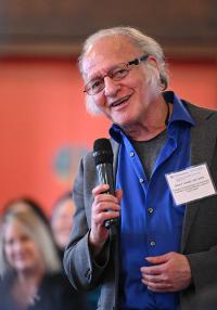 A smiling man holds a microphone