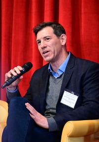 A seated man speaks into a microphone