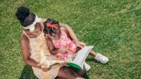 mother and child sitting on grass reading a book