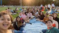 BEST students sit in a circle smiling in a New York City park on a picnic blanket