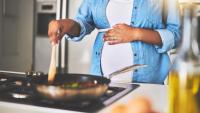 A pregnant woman cooks on a gas stove