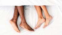 Two pairs of legs facing each other under the covers