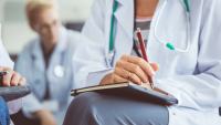 Two doctors sitting with notebooks writing