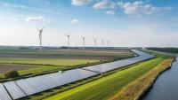 An aerial photo of a waterway, solar panel array and wind farm.