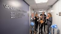 A photo of five individuals at a ribbon-cutting ceremony; Dean Linda P. Fried holds oversized scissors