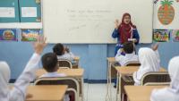 A female teacher interacts with a classroom of students in Indonesia