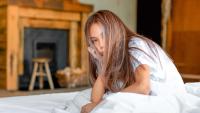 Adolescent girl sitting on her bed