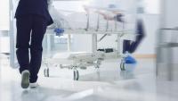 Medical staff run with a rolling hospital bed in a hallway