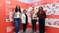 Four people pose in front of a red and white display