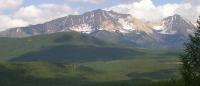 A mountain range with snow and green trees