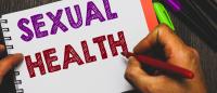 photo from above of hands writing words "sexual health" in a notebook