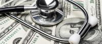 A stethoscope lies on top of a pile of $100 bills