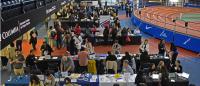 Aerial shot of people talking around long tables next to an indoor running track