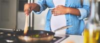A pregnant woman cooks on a gas stove