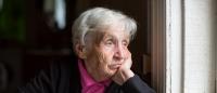 Elderly woman looking out window