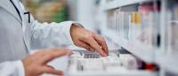 A pharmacist inspects a drawer of medicines.