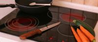An induction stovetop with pan, knife and carrots