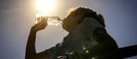 A girl drinks from a water bottle under a bright sun