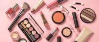 Lipstick, nail polish, blush and other cosmetics from above on a pink background