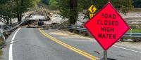 A flooded road with an orange sign reading, "Road Closed High Water."