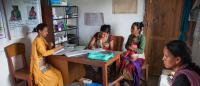 Four women and one infant sit in a clinical setting