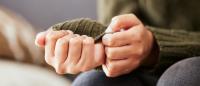 Person's nervous hands holding sweater sleeve