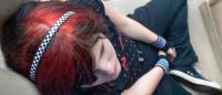 Female with colorful hair thinking in a reclining position