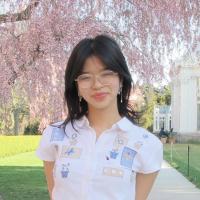Woman with glasses standing in front of a cherry blossom tree