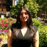 Woman wearing glasses standing in front of a garden