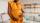 A photo of a pregnant Black woman in a yellow dress holding her belly